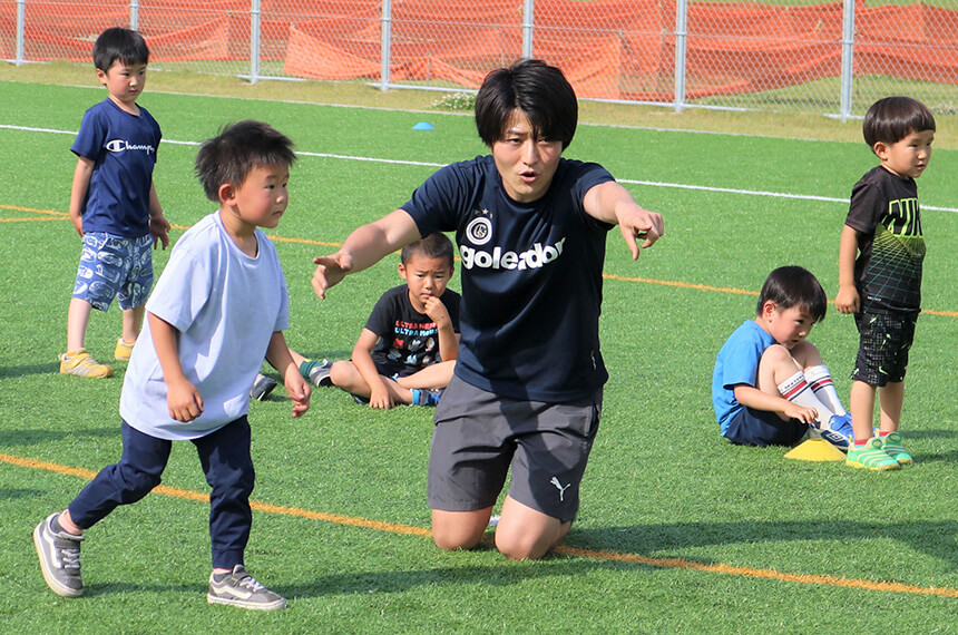 サッカーの練習をする子どもとコーチ