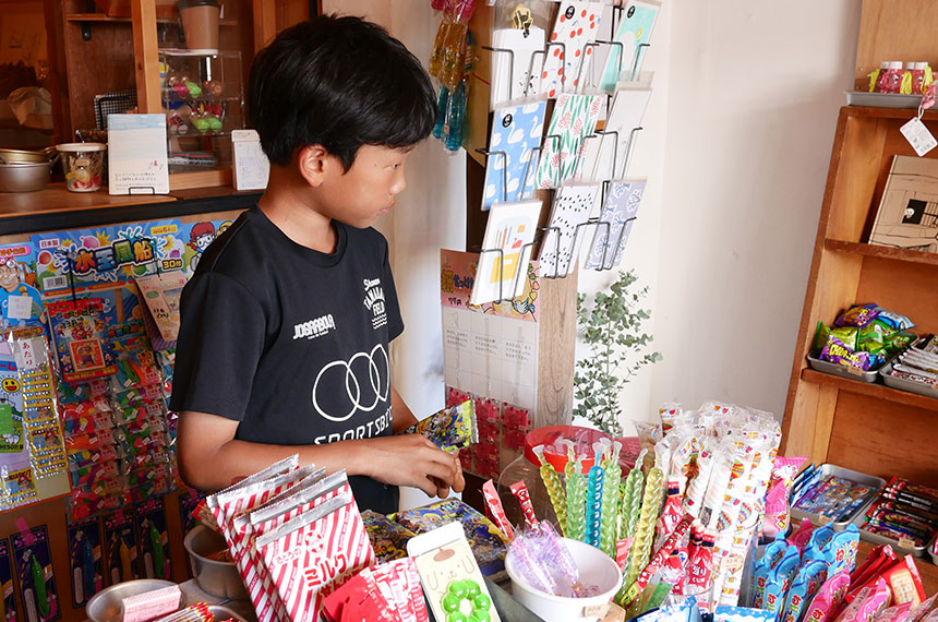 駄菓子屋さんでお菓子を選ぶ子ども