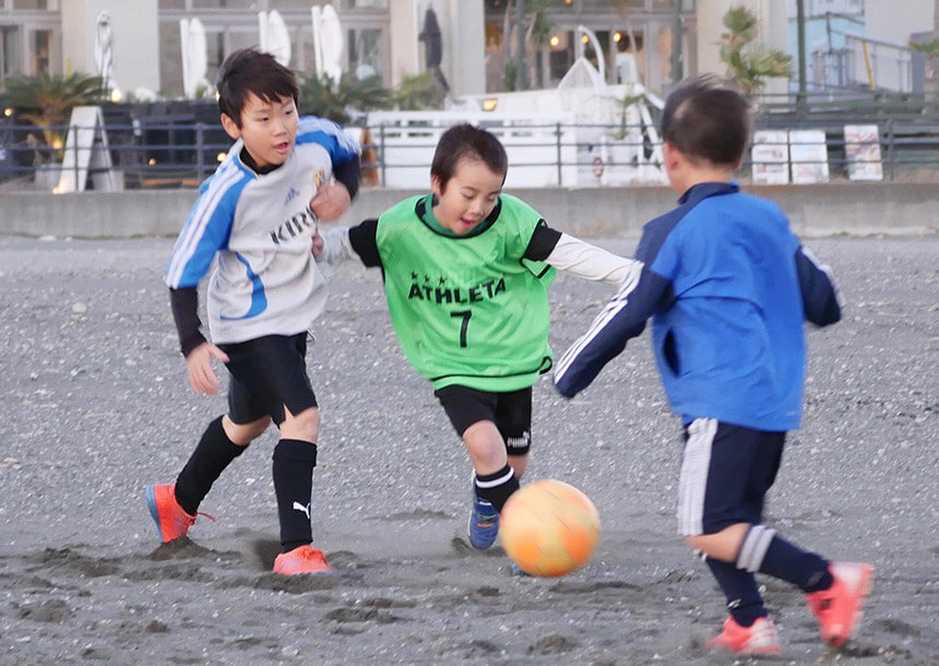 海でサッカー練習をする子ども達